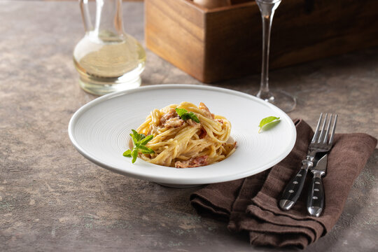 Pasta carbonara served in deep white plate with oregano