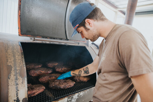 Man Checking Barbecue Meats in Smoker