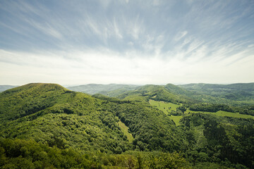 Obraz premium Beautiful scenic view of valley and big hills (mountains) in Slovakia on sunset with cloudy sky. Perfect panorama view on meadow and hills on sunset - summertime photo. Hills of Vapec - Slovakia.