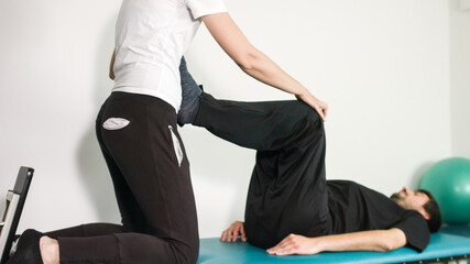 Obraz premium Physiotherapist exercising with disabled person on a therapy table.