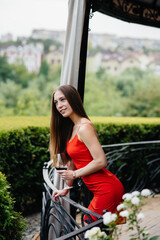 Obraz premium Beautiful young girl drinks wine on the veranda of a beautiful house. Holiday.