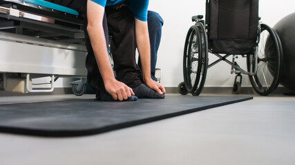Obraz premium Physiotherapist exercising with disabled person using wheelchair on a therapy table.