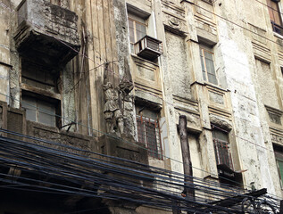 Facade of an old dilapidated building and numerous cables in Chinatown in Binondo district, Manila, Philippines