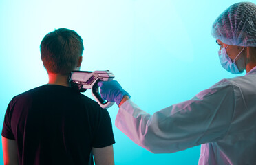 Girl doctor in uniform gives a chip injection with a syringe to a young man in the neck,...