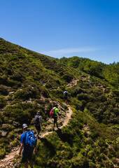 Fototapeta na wymiar varias personas caminan por senderos en el monte gorbea en un dia soleado con pocas nubes y caminos de piedras , vistas a la montaña