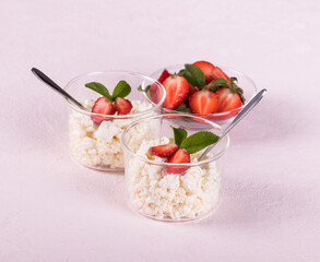 Cottage cheese with strawberries in a glass Cup on a light pink background