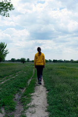 Girl in yellow walking on countryside path at early spring