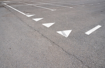 Dark asphalt road with marking lines. Tarmac texture. White disabled sign on a empty parking lot. Black tarmac texture with road marking 