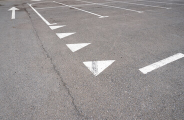 Dark asphalt road with marking lines. Tarmac texture. White disabled sign on a empty parking lot. Black tarmac texture with road marking 