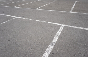 Dark asphalt road with marking lines. Tarmac texture. White disabled sign on a empty parking lot. Black tarmac texture with road marking 