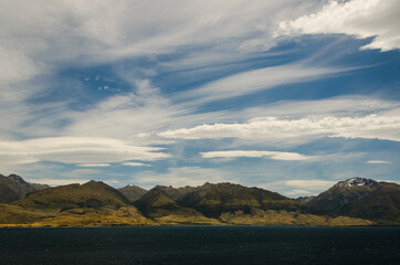 Mountains landscape with lake in front on blue cloudy sky