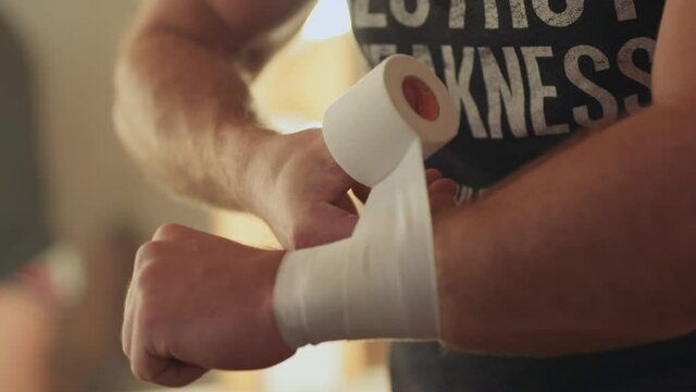 Muscular fighter taping wrists before competing in fight