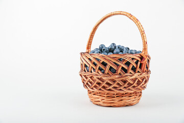 Fototapeta na wymiar blueberry berries in wicker basket on white background with copy space