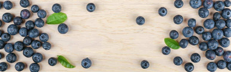  blueberry berries with green leaves on light wooden background top view 