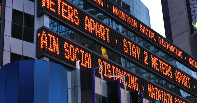 A Times Square stock market ticker reminds pedestrians to keep 2 meters apart from each other. Social distancing was a common practice to slow down the spread of COVID-19 during the pandemic of 2020. 