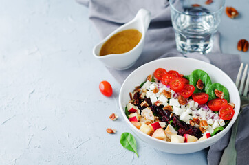 Chicken spinach apple tomato goat cheese salad in a bowl