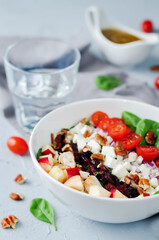 Chicken spinach apple tomato goat cheese salad in a bowl