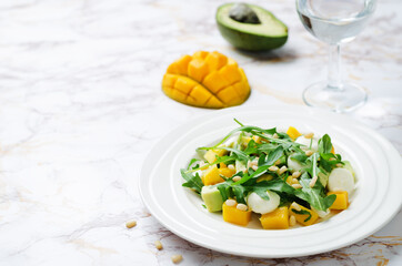 Avocado mango arugula pine nuts Mozzarella salad in a plate.