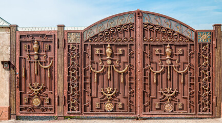 Metal gate in front of the house with wrought iron elements as a background