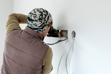 Worker cuts a hole in the wall. Installing new outlets. Work with an electric tool or angle drive...