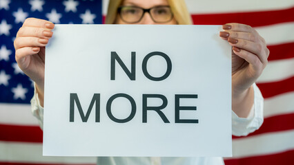 Woman holds poster NO MORE on american flag background