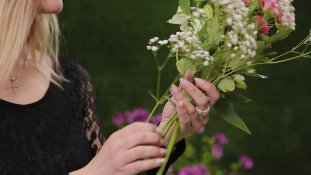 Florist cuts flower stems for a bouquet with scissors.