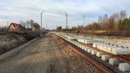 Railway works in small village. Railroad construction and modernisation site. Aerial view on excavator and railway track components.  © Bartosz