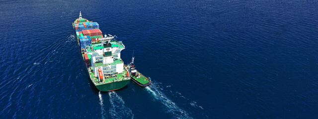 Aerial drone ultra wide photo of fully loaded container cargo ship cruising in open ocean deep blue...