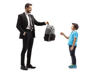 Full length shot of a father giving a backpack to his son
