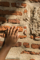Hand touching wall made of bricks in the colonial city of Santo Domingo