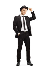 Obraz premium Full length portrait of a guy in a black suit holding his a fedora hat