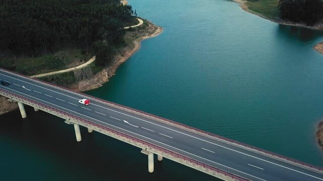 Singular birdseye view of bridge crossing river featuring cars.
