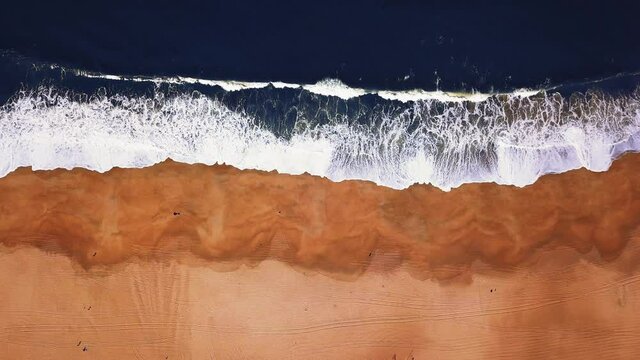 Flying over a sandy beach. Waves break on a sandy beach on the Atlantic coast, aerial View. Nazare, Portugal.