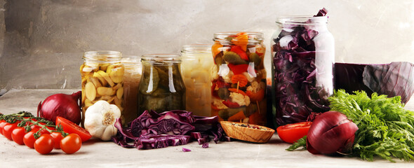 Preserves vegetables in glass jars. Pickled Cucumber, carrot, fermented cabbage and onions on rustic background