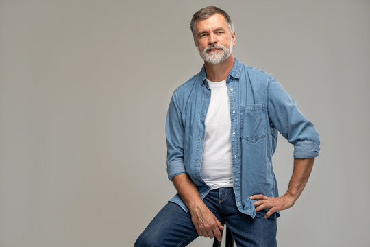 Portrait Of A Casual Senior Sitting On A Chair On White Background.