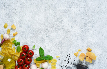 Raw pasta - Conchiglie with spices, tomatoes and basil on a concrete background. Top view.