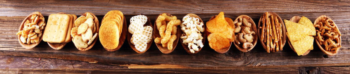 Salty snacks. Pretzels, chips, crackers in wooden bowls on table