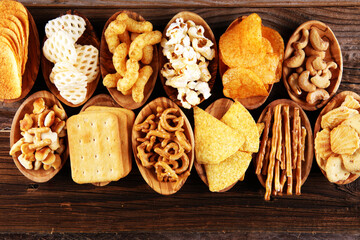 Salty snacks. Pretzels, chips, crackers in wooden bowls on table