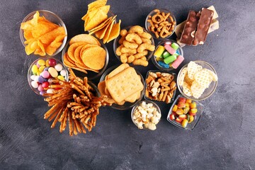 Salty snacks. Pretzels, chips, crackers in glass bowls on table