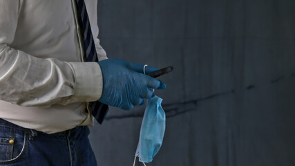 Persona con mascarilla y guantes protectores usando un teléfono movil, concepto de los nuevos objetos cotidianos a causa del virus