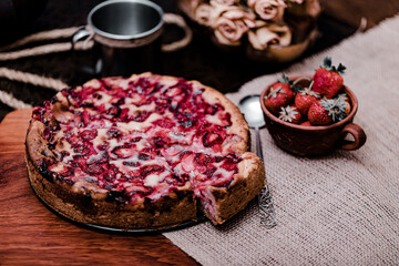 Wodden cake board with homemade strawberry cake on dark stone table and black background.