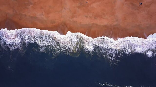 Flying over a sandy beach. Waves break on a sandy beach on the Atlantic coast, aerial View. Nazare, Portugal.