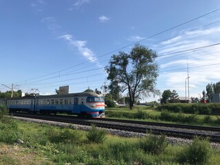 Fototapeta na wymiar electric train rides through the city against the sky and greenery