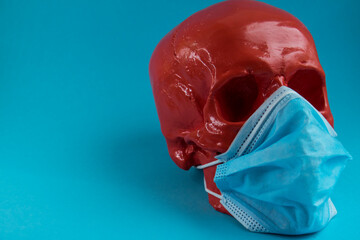 Red scary skull in a medical mask lies on a blue background