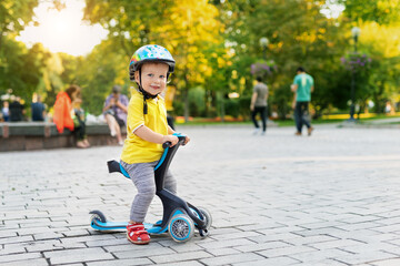 Cute adorable little caucasian toddler boy portrait in helmet having fun riding three-wheeled balance run bike scooter in city park or forest. Child first bike. Kids outdoor sport activities © Kyryl Gorlov