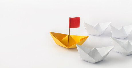 Leadership concept. Red flag Origami Yellow Paper boat (ship) leading the other white boats.  One...