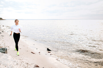 Evening jog on the seashore. A beautiful girl with a sports figure dressed in sportswear jogging...