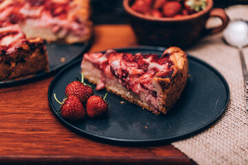Pie with rhubarb and organic strawberries on a dark wooden background with fresh strawberries. Selective focus and vintage image.