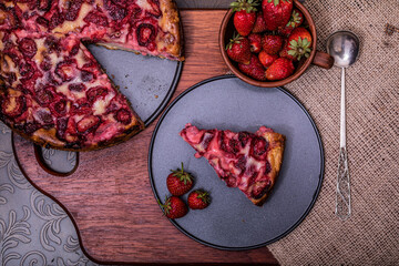 Pie with rhubarb and organic strawberries on a dark wooden background with fresh strawberries. Selective focus and vintage image.