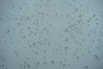 rain drops close-up sticking on the window pane in heavy downpour with cloudy sky on the background
